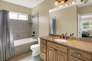 North Basement Bathroom with connected bathroom, vanity, tile patterned floors, toilet, and tiled shower / bath combo