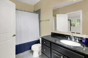 South Basement Bedroom Bathroom Full bath with tile patterned floors, toilet, curtained shower, and vanity