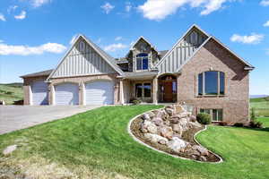 View of front of home featuring a garage, brick siding, board and batten siding, and a front lawn