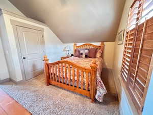 Bedroom with vaulted ceiling, carpet floors, and baseboards