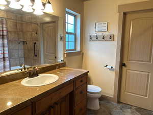 Primary bathroom with tiled shower, toilet, and vanity