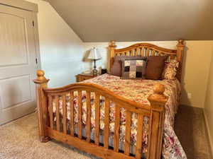 Bedroom featuring lofted ceiling, carpet flooring, and baseboards