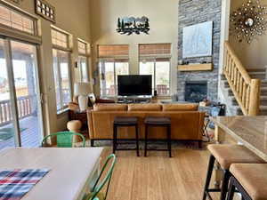 Living room featuring stairs, wood finished floors, a stone fireplace, and a high ceiling
