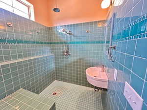 ADU Bathroom featuring tile patterned flooring, tile walls, a sink, and tiled shower