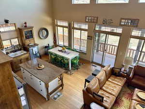 Living area with a wealth of natural light, a towering ceiling, and light wood-style flooring