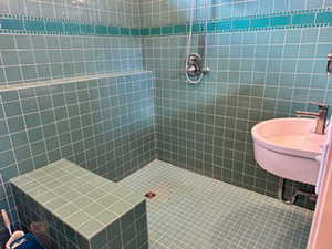 ADU Bathroom with a tile shower, tile walls, and a sink