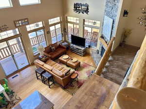 Living room featuring wood finished floors, a towering ceiling, and a stone fireplace