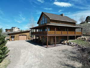 Front entry house with 3 sided covered  deck, circular driveway, and a detached garage.