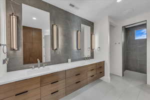 Bathroom with tile walls, double vanity, light tile patterned flooring, and recessed lighting
