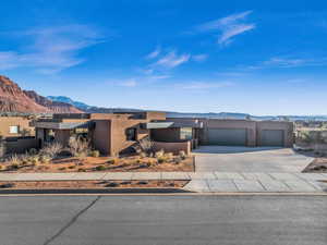 View of front facade featuring a mountain view, stucco siding, driveway, and an attached garage