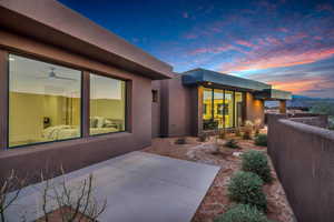 Back of property at dusk with stucco siding and a patio
