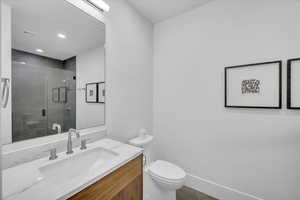 Bathroom featuring toilet, vanity, a shower stall, and recessed lighting