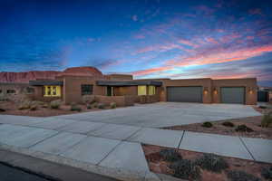 Pueblo revival-style home with stucco siding, concrete driveway, and a garage