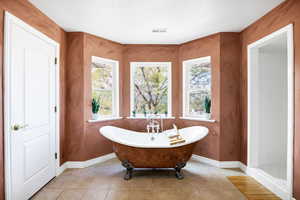 Full bathroom featuring visible vents, a freestanding tub, tile patterned floors, and baseboards