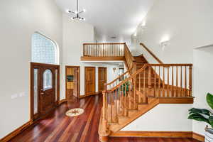 Foyer entrance featuring stairway, visible vents, baseboards, a towering ceiling, and wood finished floors