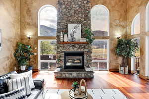 Living area with a towering ceiling, wood finished floors, and a fireplace