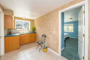 Kitchen with a sink, brown cabinets, decorative backsplash, light tile patterned floors, and baseboards