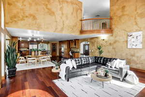 Living room featuring visible vents, baseboards, arched walkways, dark wood-type flooring, and a high ceiling
