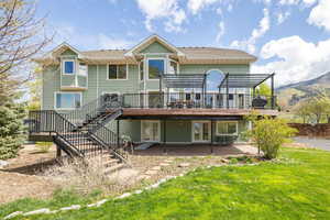 Back of property with a pergola, stairway, a yard, a deck with mountain view, and french doors