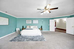 Carpeted bedroom with ornamental molding, a ceiling fan, visible vents, and baseboards
