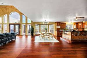 Dining space with a textured ceiling, dark wood-style flooring, and an inviting chandelier