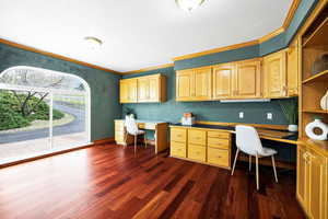 Office space with crown molding, baseboards, dark wood finished floors, and built in study area
