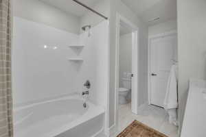 Bathroom featuring marble finish floor, visible vents, toilet, and shower / bathtub combination with curtain