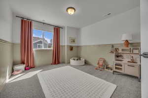 Bedroom featuring a wainscoted wall, visible vents, and carpet