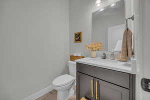 Bathroom with baseboards, wood finished floors, toilet, and vanity
