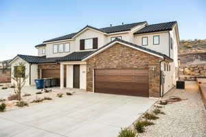 Modern inspired farmhouse with a tiled roof, stucco siding, concrete driveway, and stone siding