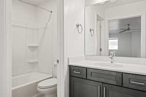 Bathroom featuring toilet, a ceiling fan, washtub / shower combination, and vanity