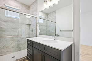Full bathroom featuring a stall shower, a healthy amount of sunlight, wood finished floors, and vanity