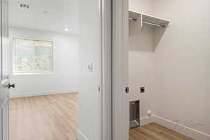Washroom featuring laundry area, electric dryer hookup, visible vents, baseboards, and wood finished floors