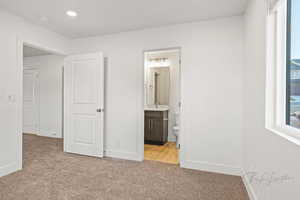 Unfurnished bedroom with a sink, baseboards, recessed lighting, and light carpet