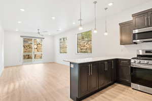Kitchen with stainless steel appliances, light countertops, light wood-type flooring, a ceiling fan, and a peninsula