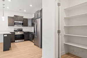 Kitchen with stainless steel appliances, light countertops, dark brown cabinets, recessed lighting, and light wood finished floors