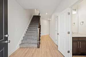 Stairway with wood finished floors, recessed lighting, and baseboards