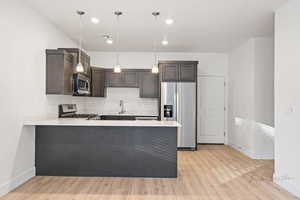 Kitchen featuring stainless steel appliances, baseboards, light wood-style flooring, and a sink