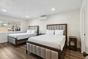 Bedroom featuring wood finished floors, a wall mounted air conditioner, recessed lighting, and baseboards