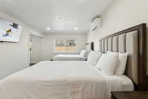 Bedroom with recessed lighting, an AC wall unit, and a closet