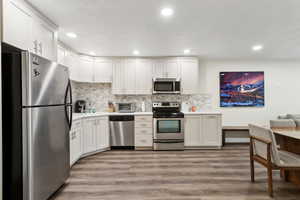 Kitchen featuring tasteful backsplash, appliances with stainless steel finishes, light countertops, light wood finished floors, and a sink