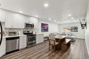 Kitchen with stainless steel appliances, light wood-style floors, tasteful backsplash, a toaster, and open floor plan