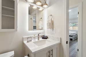 Half bath featuring wood finished floors, toilet, and vanity