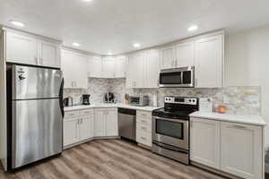 Kitchen with a toaster, stainless steel appliances, light wood-style floors, light countertops, and a sink