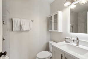 Bathroom featuring tiled shower, toilet, and vanity