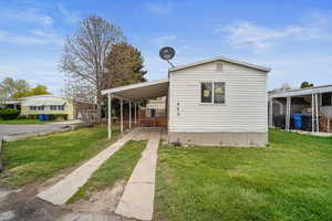 Exterior space with driveway, a carport, and a front yard