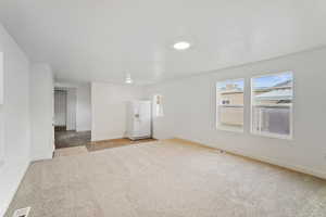 Interior space with baseboards, visible vents, and light carpet
