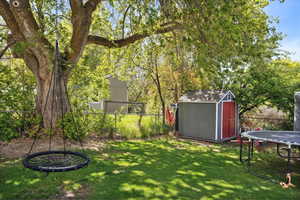 View of yard featuring an outbuilding, a storage shed, a trampoline, and a fenced backyard