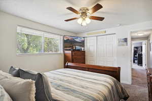 Bedroom with carpet, a ceiling fan, a textured ceiling, and a closet
