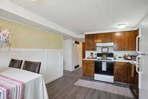 Kitchen featuring visible vents, light countertops, under cabinet range hood, electric range, and dark wood-type flooring